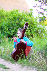 Cute girl playing guitar outdoors