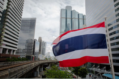 Low angle view of flag against buildings in city against sky