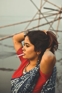 Side view of young woman with hand in hair smoking cigarette