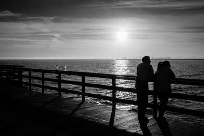 Silhouette couple standing on beach against sky during sunset