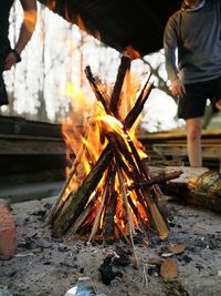 Man standing by burning campfire at campsite