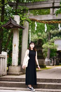 Portrait of a smiling young woman standing against built structure