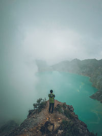 Rear view of man standing on mountain against sky