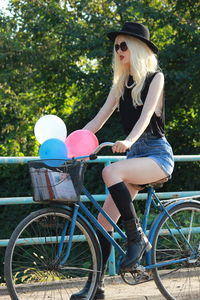 Full length of woman with bicycle against plants