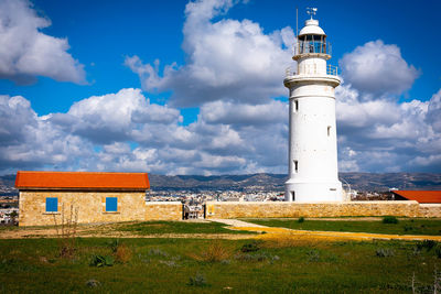 Lighthouse amidst buildings against sky