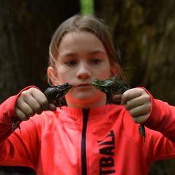 Close-up of girl holding two frogs
