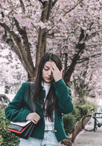 Portrait of young woman standing against trees