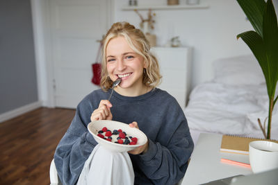 Portrait of young woman having food at home