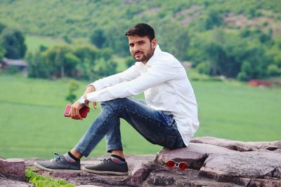 Portrait of young man sitting on rock