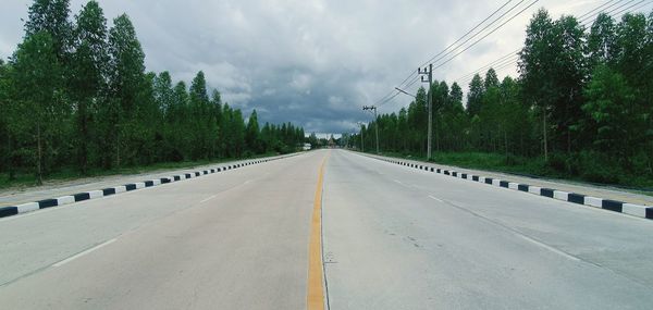 Empty road amidst trees against sky