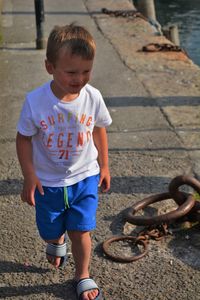 Full length of boy holding metal on footpath