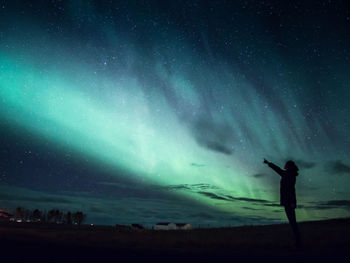 Silhouette man standing on field against sky at night