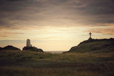 Lighthouse on field against sky during sunset