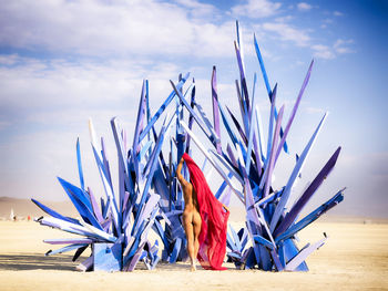 Woman sitting on beach against sky