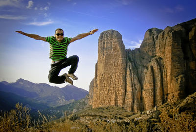 Man jumping on mountain against sky