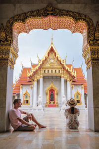 Wat benchamabophit temple in bangkok, asian woman with hat and european men visiting a temple