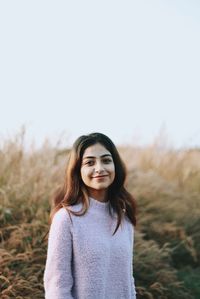 Portrait of young woman standing against sky