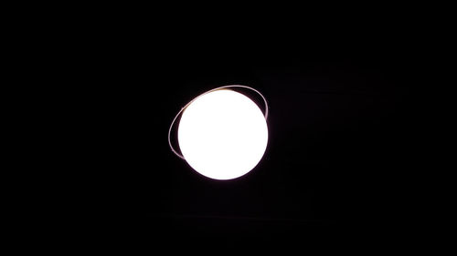 Low angle view of illuminated lamp against black background