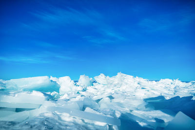 Snow covered landscape against blue sky