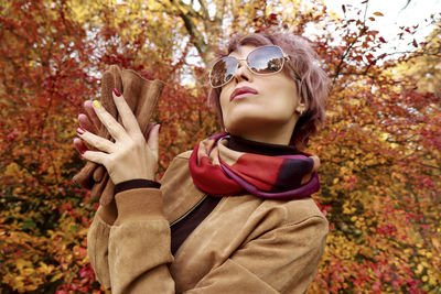 Portrait of woman wearing sunglasses against trees during autumn