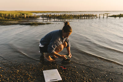 Woman washing dishes in sea