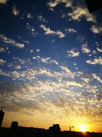 Silhouette city against sky during sunset