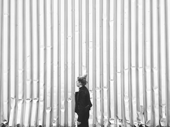 Side view of woman standing by damaged corrugated iron