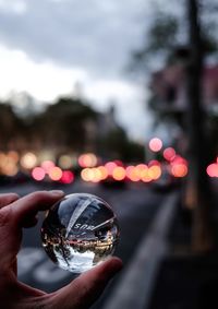 Close-up of hand holding crystal ball against blurred background