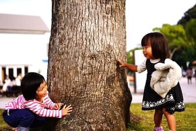 Full length of mother and daughter on tree trunk