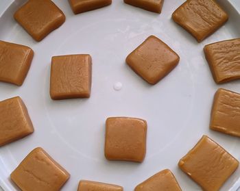 Close-up of homemade caramel candy squares on white plate