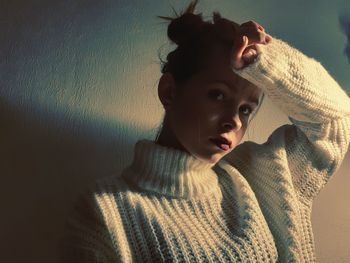 Portrait of young woman looking away against wall