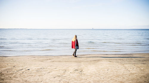 Rear view of woman walking on shore at beach