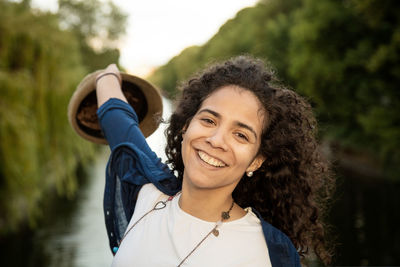 Portrait of smiling young woman holding hat