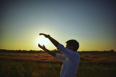 Man on field against clear sky during sunset