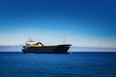 Ship sailing on sea against blue sky