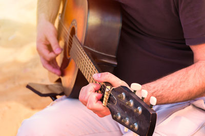 Midsection of man working with guitar