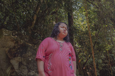 Full length of woman standing by tree in forest