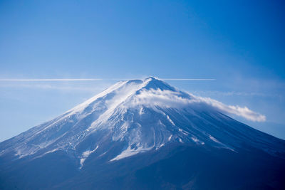 Aerial view of snowcapped mountains against blue sky 