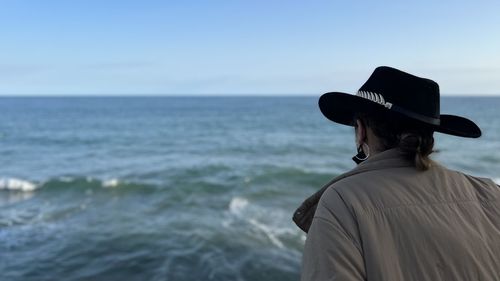 Rear view of man standing at beach against clear sky