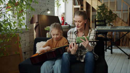 Mother teaching guitar to daughter