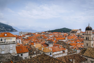 High angle view of townscape by sea against cloudy sky