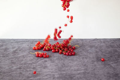 Close-up of red berries on table against white background