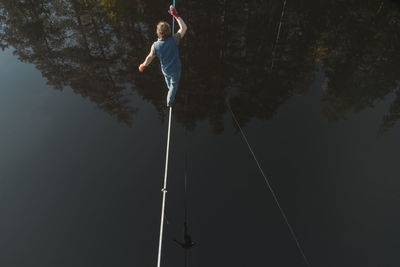 The tightrope walker walks over the water. aerial view. themes of slackline, highline and waterline.