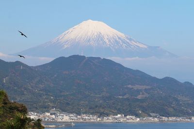 Scenic view of sea by mountain against sky