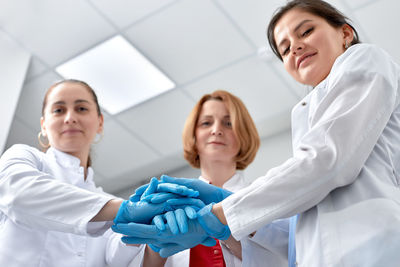 Low angle portrait of doctors stacking hands