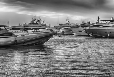 Boats moored at harbor against sky