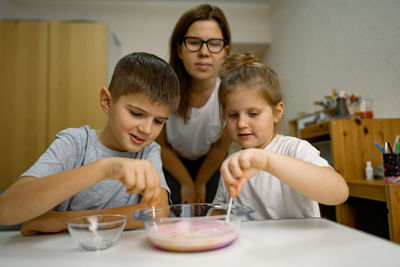 Mom and children are having fun at home, experimenting with milk and paints