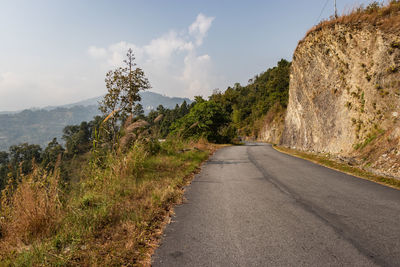 Isolated road amidst trees against sky