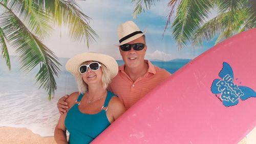 Portrait of smiling mature couple with surfboard at beach