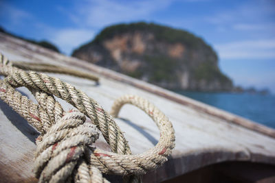 Close-up of tied rope on boat in sea against mountain